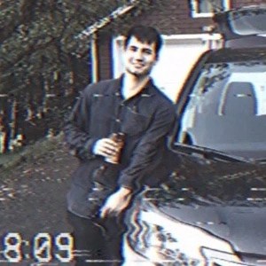 VHS-like video still of person leaning on car